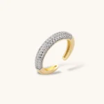 Gold-plated curved necklace, hoop earrings, and adjustable ring with pavé cubic zirconia stones on cream background.
