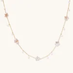 Gold vermeil chain with iridescent star-shaped baroque pearls and small round freshwater pearl drops on cream background.