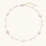 Gold vermeil chain with iridescent star-shaped baroque pearls and small round freshwater pearl drops on cream background.
