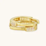 Close-up of gold-plated sterling silver huggie hoop earrings featuring rectangular cubic zirconia stones on neutral background.