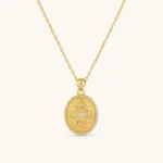 Oval gold coin pendant with pave CZ mandala motif and beaded border on an 18K gold-plated cable chain.
