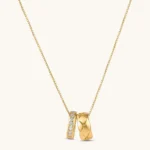 Gold box-chain necklace with two interlocking ring pendants — one star-engraved, one pavé cubic zirconia, 18K gold-plated.